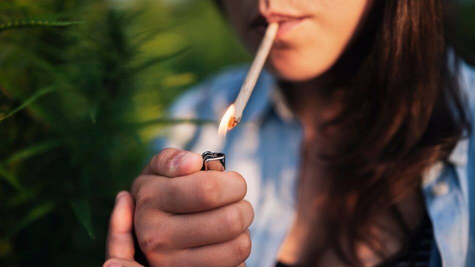 Women holding a lighter sparking a perfectly rolled joint.
