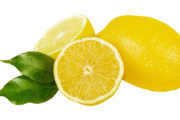 A lemon cut in half with 2 green leaves inbetween and a whole uncut lemon next to them.