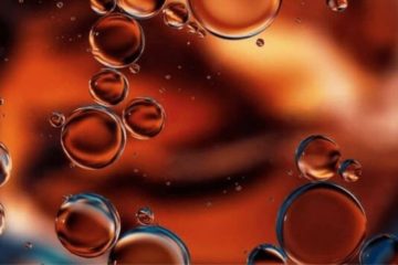 Oil droplets floating vertically in water.