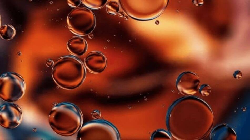 Oil droplets floating vertically in water.
