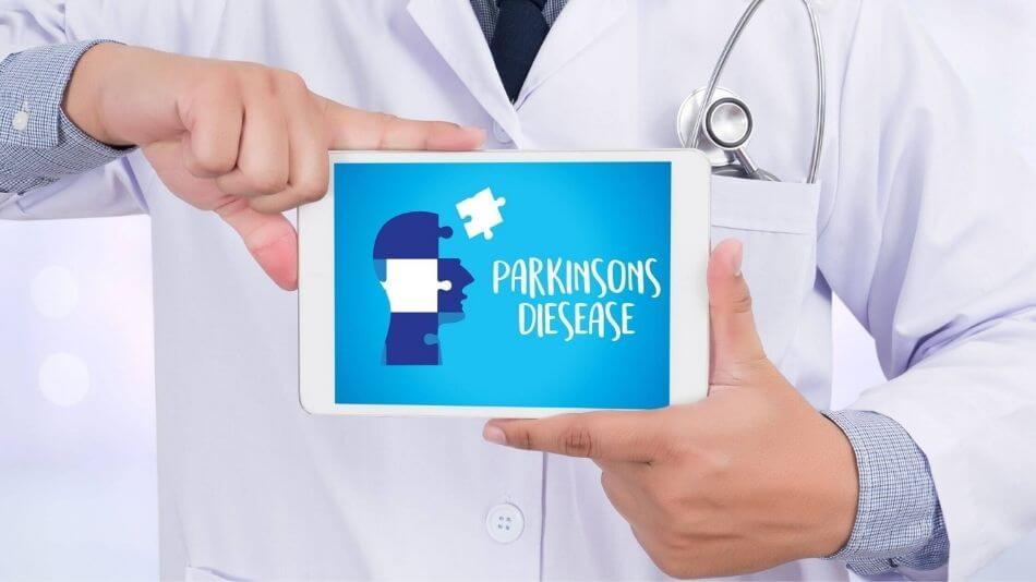 Doctor wearing white residency jacket holding an iPad with a picture of an animated head and the words Parkinson's disease.