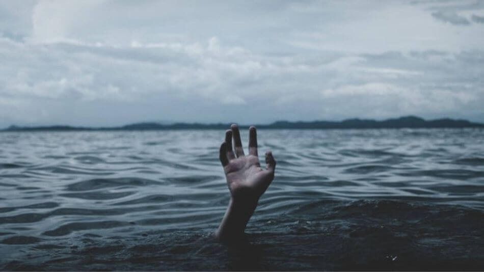 Hand fighting to stay above water with ominous clouds above and dark shadows in front.