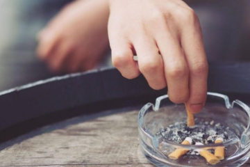 A mans hand stamping out aa cigarette butt in an ashtray.