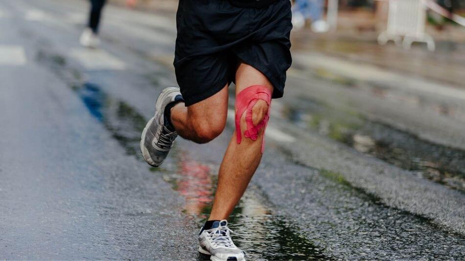 Man running with support tape wrapped around his knee.