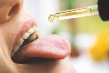 Women dropping CBD oil onto her tongue.