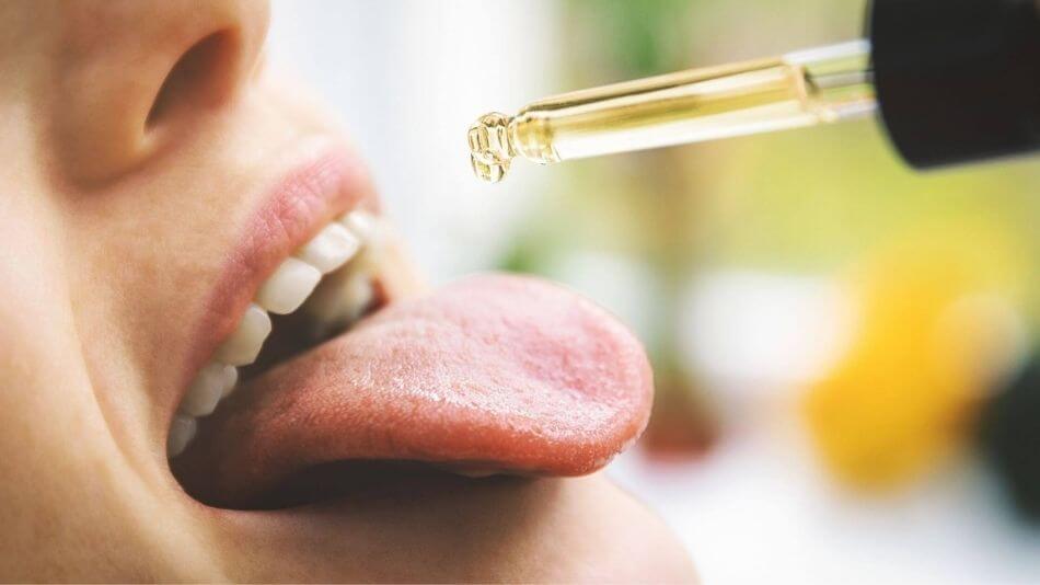 Women dropping CBD oil onto her tongue.