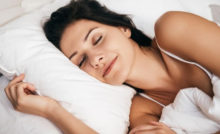 Dark haired middle aged women sleeping in a white tanktop.