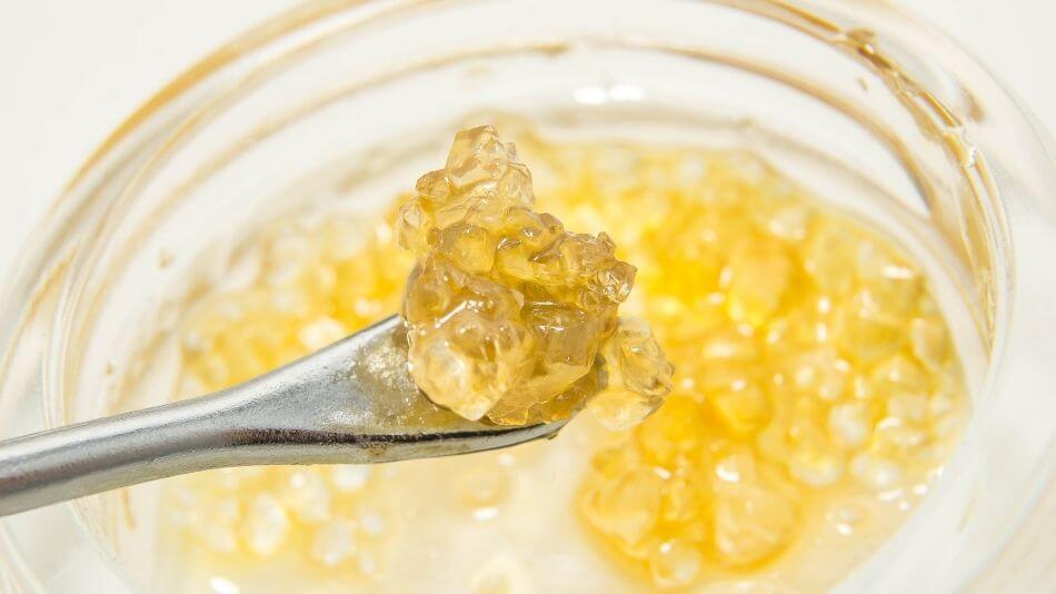 Raw CBD isolate crystals being scooped up by a dab tool.