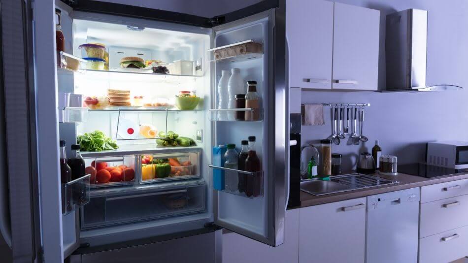 An open refrigerator with the light on full of food.