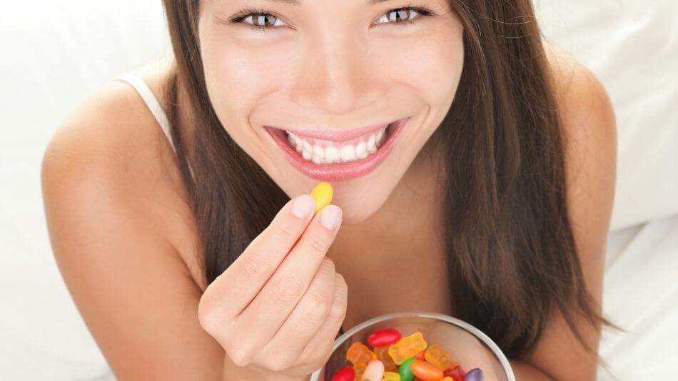 Brunette women with brown eyes holding a bowl of gummy bears smiling ear to ear.