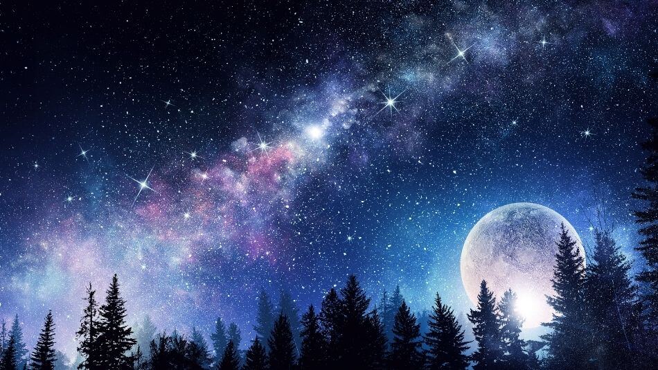 Galaxy photo with the moon in the bottom right corner and trees on the bottom edge.