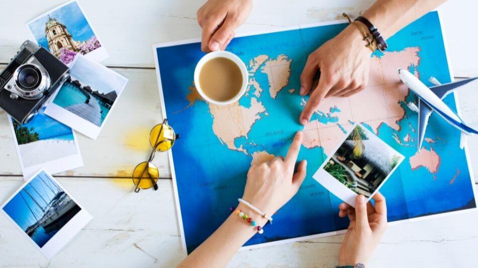 Two people pointing at a spot off the coast of Africa on a map laying on the table.