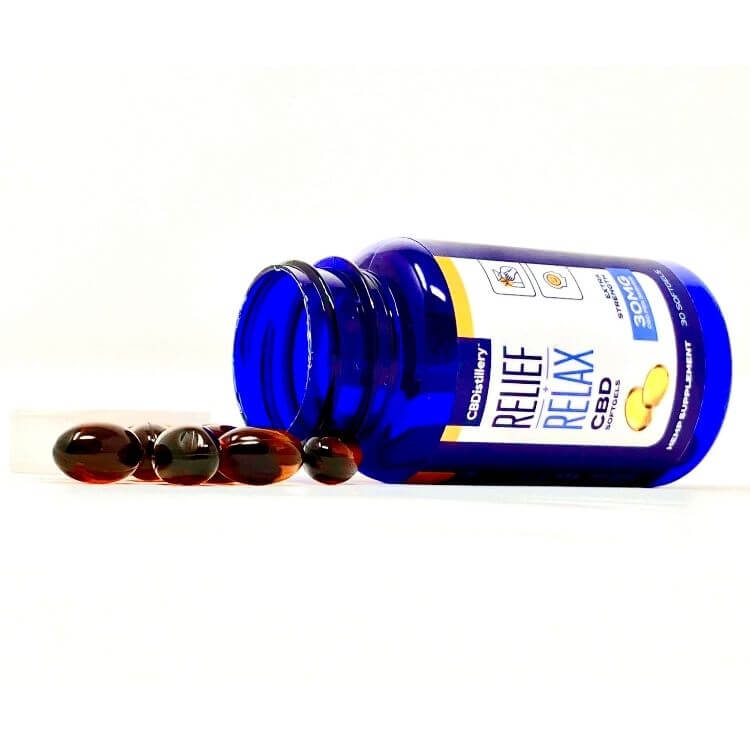 Bottle of CBDistillery full spectrum softgels laying on its side with a pile of softgels spilling out.