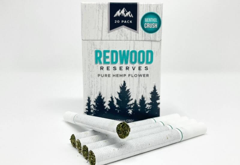 Redwood Reserve menthol CBD hemp flower cigarette box with five cigarettes laying in front.