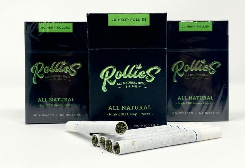 3 packs of Rollies original high CBD hemp flower cigarettes with 5 cigarettes laying in front.