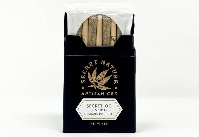 Pack of seven Secret Nature Secret OG prerolls with the top open and the hermetically sealed bag popping out.