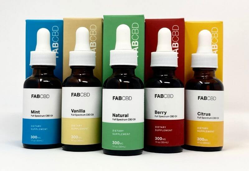 All five flavors of FAB CBD oil standing next to each other with the matching boxes behind each bottle.